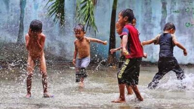 Hujan sering dianggap sebagai momok bagi orangtua yang khawatir tentang kesehatan dan kondisi anak. Namun, membiarkan anak (Sumber foto : Tribunews)