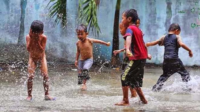 Hujan sering dianggap sebagai momok bagi orangtua yang khawatir tentang kesehatan dan kondisi anak. Namun, membiarkan anak (Sumber foto : Tribunews)